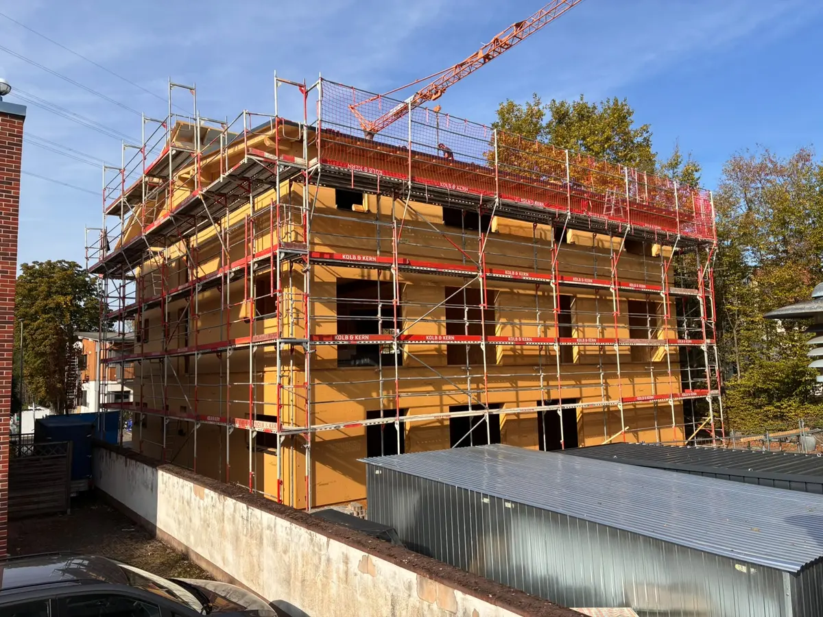 Der Rohbau vom Hof aus: drei Geschosse im Gerüst, Oktober 2026
